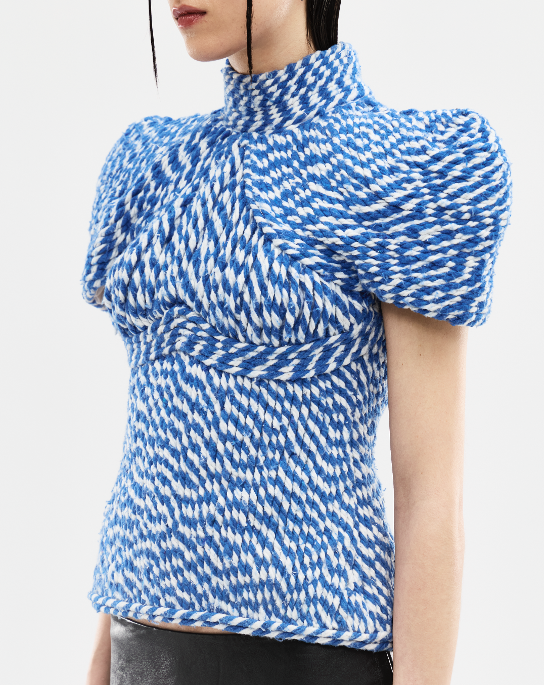 Blue and white patterned top worn by a person on a light gray background
