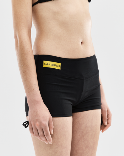 Person wearing black shorts with a visible brand logo on a white background